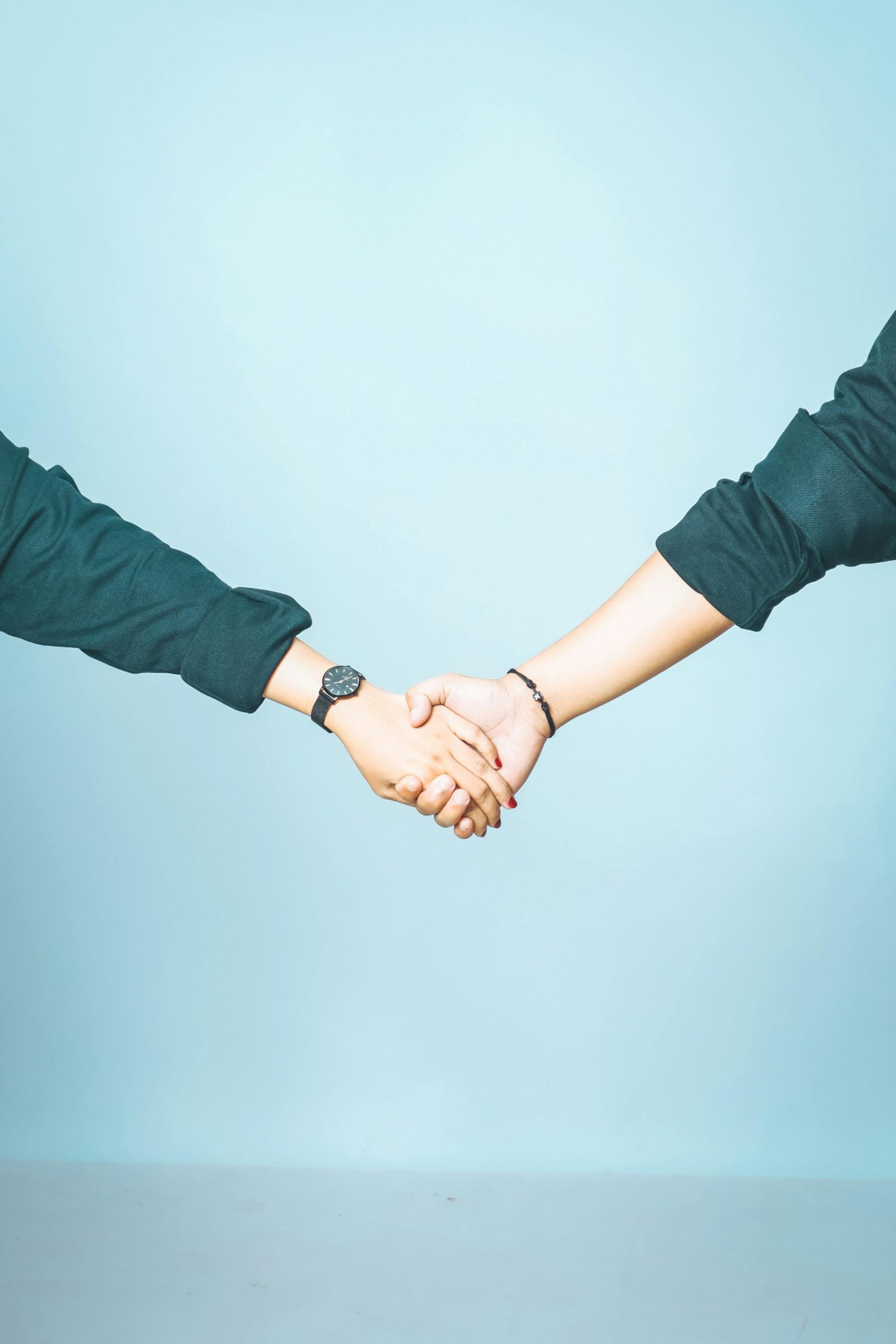 Close-up of two people shaking hands against a blue background, signifying agreement and partnership.