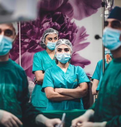 Răspundere civilă profesională Surgeons and nurses in scrubs preparing for surgery, showcasing teamwork in a hospital setting.