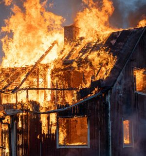 ASIGURARI LOCUINTA A house consumed by intense flames and smoke, capturing the power of fire.