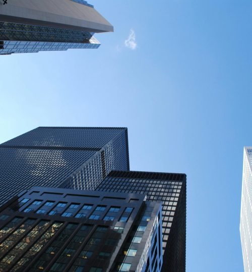 Projects Low angle view of modern skyscrapers with a clear blue sky background.