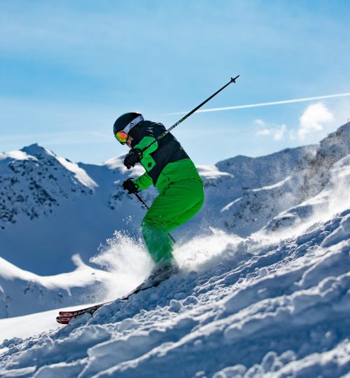Projects Skier in vibrant green outfit carving through snowy slopes in Vorarlberg, Austria.