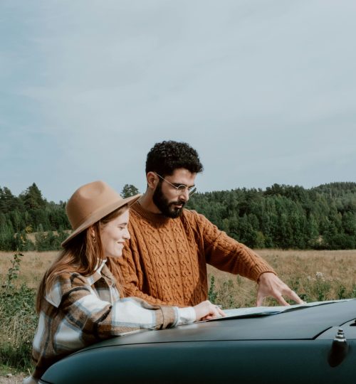Projects Young couple planning travel route with map on car hood in scenic outdoor setting. Perfect for travel and adventure themes.