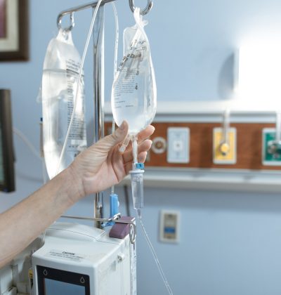 Sănătate și accidente Close-up image of an IV drip and hand in a hospital room, illustrating medical care.